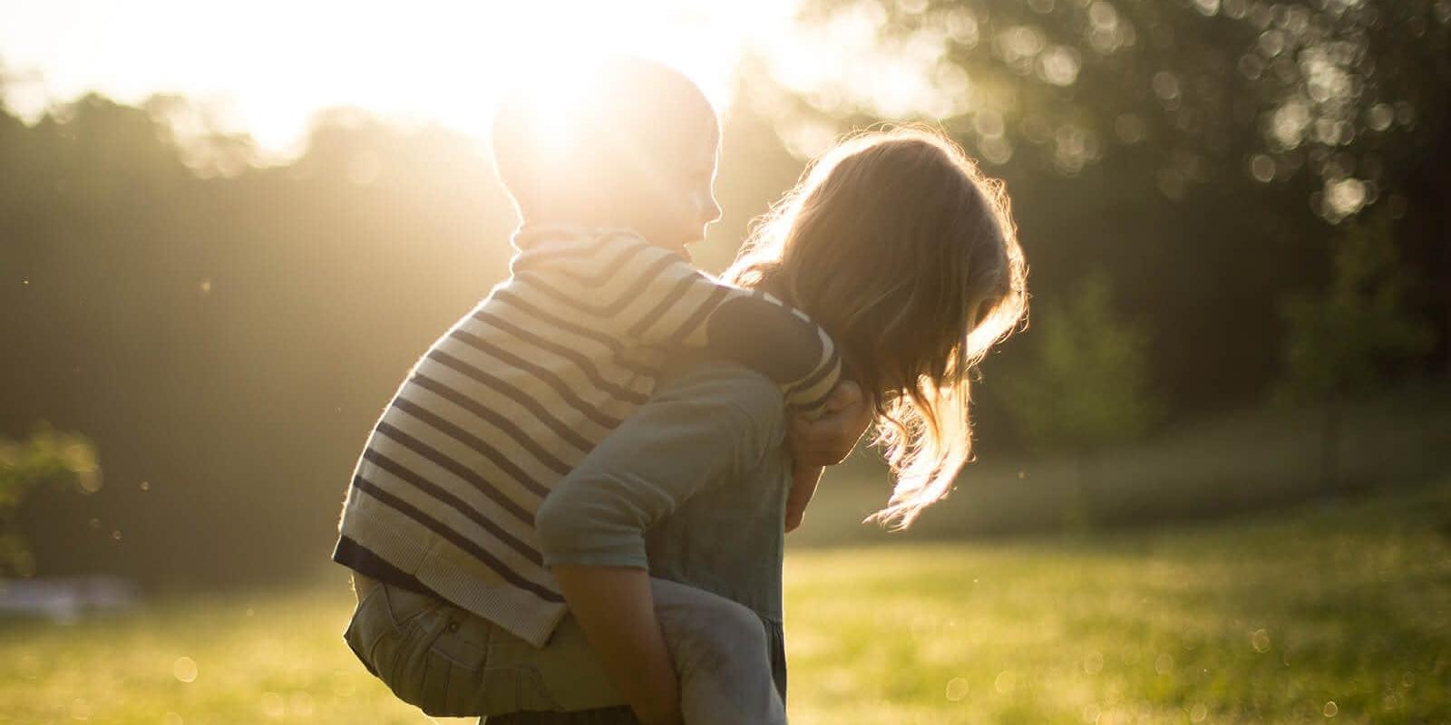 Kind wird huckepack getragen im Sonnenlicht